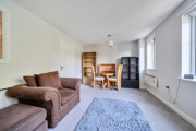 Living room with sofas, dining table, shelving unit and windows.