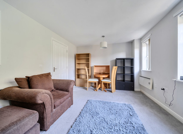 Living room with sofas, dining table, shelving unit and windows.
