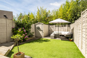 Garden with a lawn, planting beds, shed and outdoor seating area.