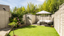 Garden with a lawn, planting beds, shed and outdoor seating area.