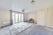 Bright living room with grey carpet, patterned rug and French doors to garden
