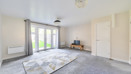 Bright living room with grey carpet, patterned rug and French doors to garden