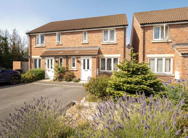 A semi-detached house house with a landscaped front garden and driveway.