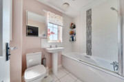 Bathroom with toilet, pedestal sink and bathtub with shower screen.