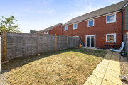 Enclosed rear garden with lawn, paved path, and wooden fencing.