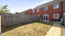 Enclosed rear garden with lawn, paved path, and wooden fencing.