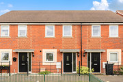 Front view of a red brick terraced houses with black entrance doors.