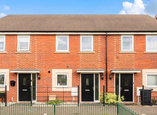 Front view of a red brick terraced houses with black entrance doors.