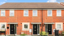 Front view of a red brick terraced houses with black entrance doors.