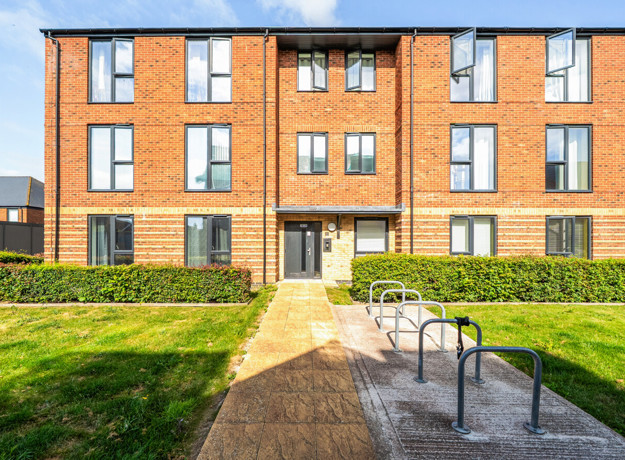 Apartment building with brick exterior, pathway, and bicycle racks.