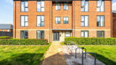 Apartment building with brick exterior, pathway, and bicycle racks.
