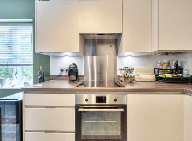 Kitchen worktop with built-in oven, extractor hood and countertop appliances.