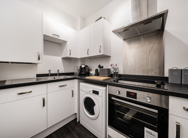 Kitchen with integrated appliances, white units, and tiled backsplash.