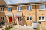 A brick terraced house with front garden, pink front door and paved access path.