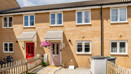 A brick terraced house with front garden, pink front door and paved access path.