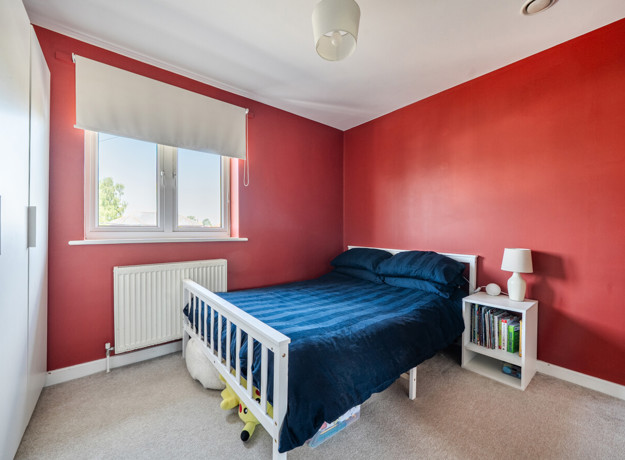 Bedroom with a double bed, bedside tables and red feature walls.