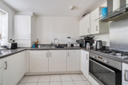 Modern white kitchen with cabinets, gas hob, and black countertops.