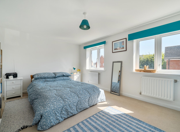 Bedroom with double bed, large window and fitted storage units.