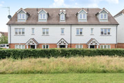 Row of terraced houses with white walls and grass area in foreground.