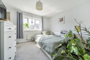 Bedroom with bed, white furniture, and plants by the window.