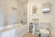 Bathroom with bath, shower screen, sink, toilet and wall mirror.