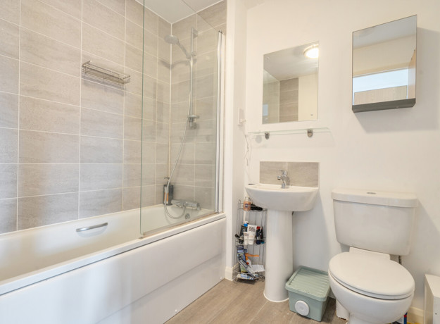 Bathroom with bath, shower screen, sink, toilet and wall mirror.
