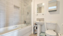 Bathroom with bath, shower screen, sink, toilet and wall mirror.