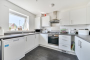 Kitchen with white cabinets, appliances, sink and a window.