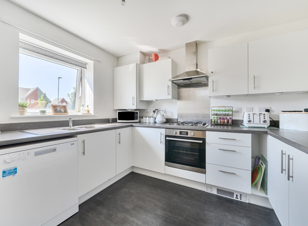 Kitchen with white cabinets, appliances, sink and a window.