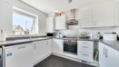 Kitchen with white cabinets, appliances, sink and a window.
