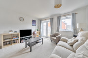 Living room with sofas, coffee table, television and patio doors.