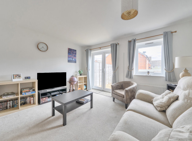 Living room with sofas, coffee table, television and patio doors.