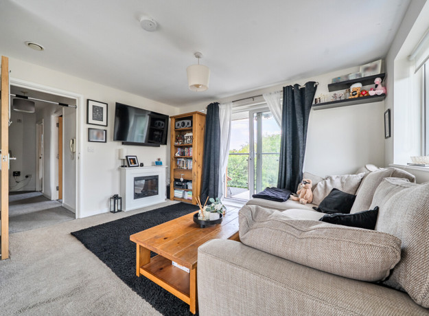 Living room with a sofa, coffee table, wall-mounted TV and balcony doors.