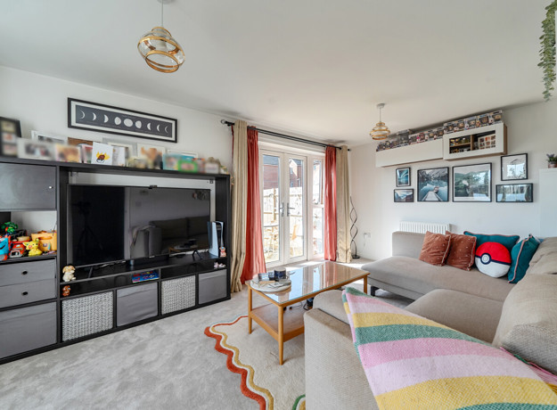 Living room with corner sofa, television unit and patio doors.