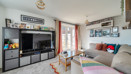 Living room with corner sofa, television unit and patio doors.