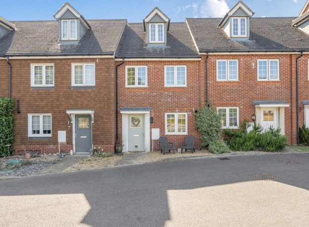 Row of red brick terraced houses with parking spaces at the front.