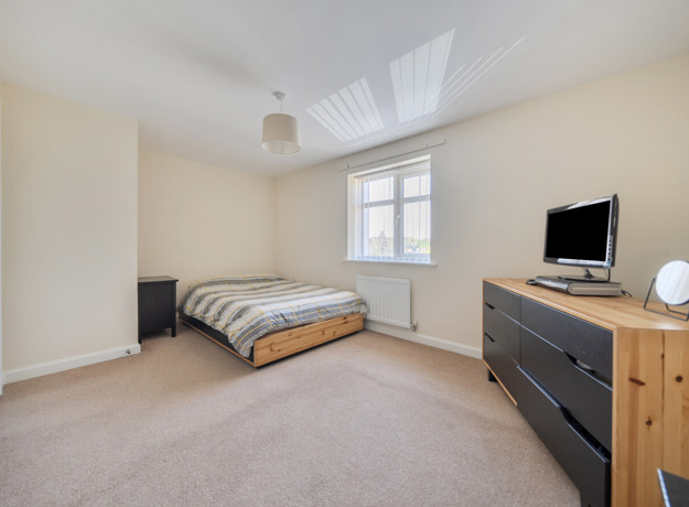 Spacious double bedroom with bed, chest of drawers and neutral decor
