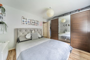 Bedroom with bed, wardrobe, wall decor and wooden-effect flooring.