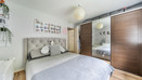 Bedroom with bed, wardrobe, wall decor and wooden-effect flooring.