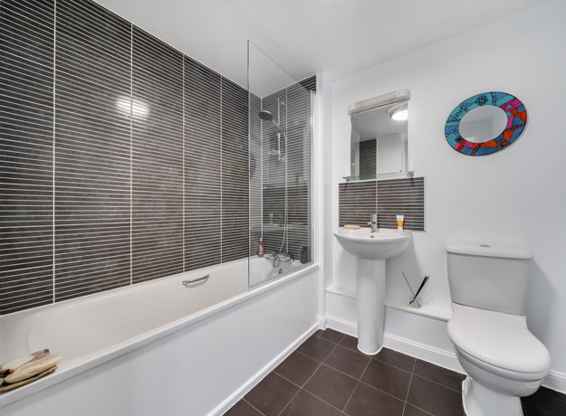 Bathroom with bathtub, wall tiles, sink and toilet.