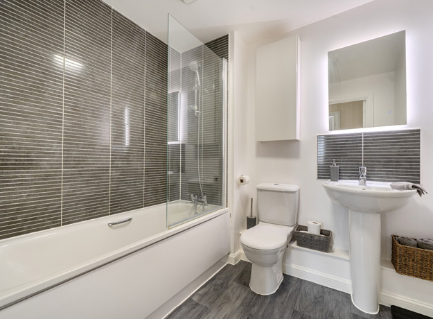 Bathroom with bathtub, toilet, sink, and tiled walls.