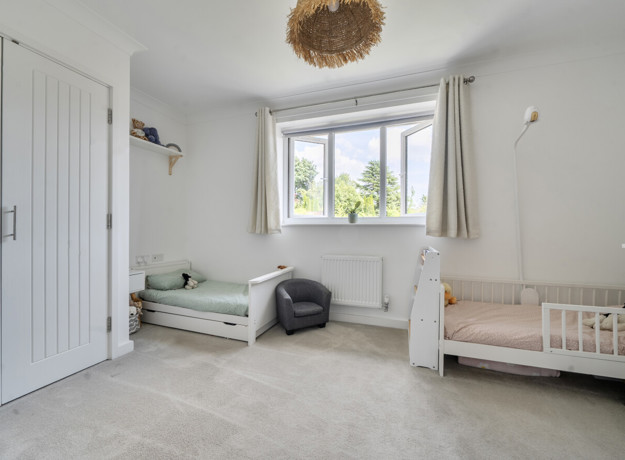 Bedroom with built-in wardrobes, two children's beds and a window.
