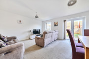 Living room with sofas, TV, dining table, and doors to the garden.