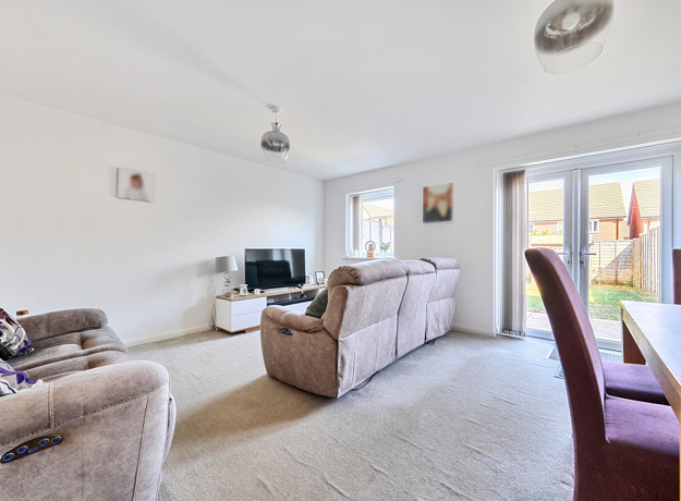 Living room with sofas, TV, dining table, and doors to the garden.
