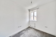 Empty bedroom with window and grey carpet.