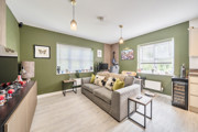 Open-plan living room and kitchen with sofa, windows and dining table.