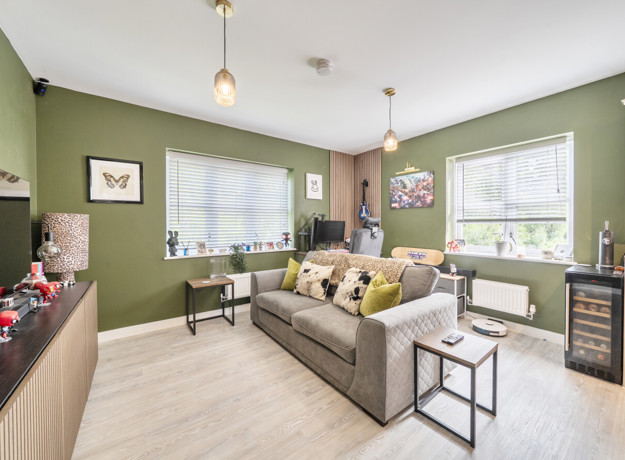 Open-plan living room and kitchen with sofa, windows and dining table.