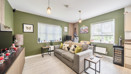 Open-plan living room and kitchen with sofa, windows and dining table.