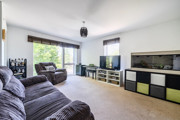 Living room with sofas, TV, stprage cupboards and large windows.