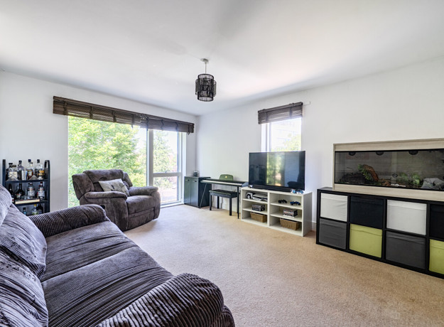 Living room with sofas, TV, stprage cupboards and large windows.